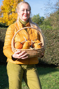 Middle-aged blond caucasian woman in a yellow demi-season jacket with pumpkins