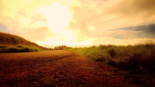 Scenic view of grassy field against cloudy sky during sunset