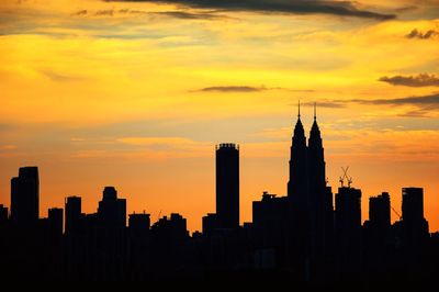 Silhouette of buildings against cloudy sky during sunset