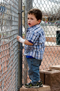 Child behind a metal fence  watching a baseball game
