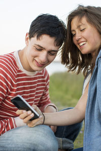 Teenage girl showing smart phone to boyfriend