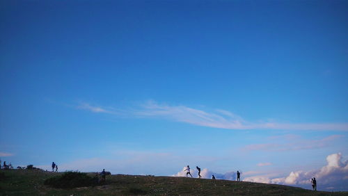 People walking landscape against blue sky