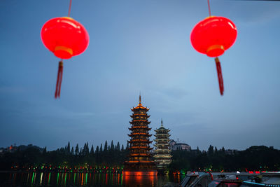 Low angle view of illuminated lanterns by building against sky