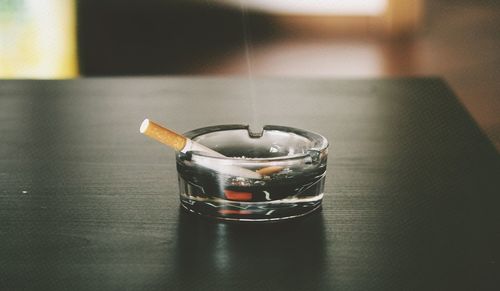 Close-up of cigarette in ashtray on table