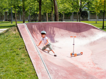  boy fell off kick scooter while riding in skate park.special concrete bowl structures, urban park.