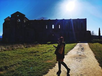 Rear view of woman walking on field against building