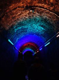 Rear view of people in illuminated tunnel