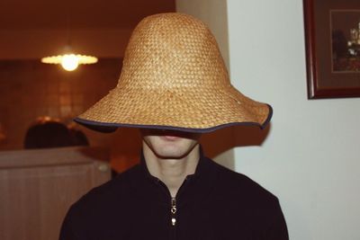 Man wearing wicker hat in illuminated room