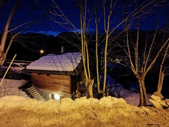Illuminated house on field against sky at night