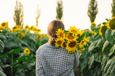 Beautiful young woman with sunflowers enjoying nature and laughing on summer sunflower field.