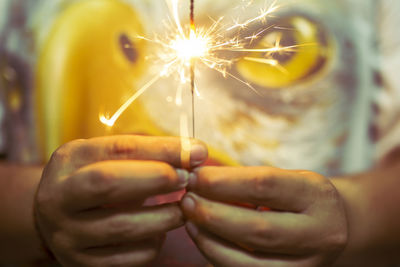 Midsection of person holding lit sparkler