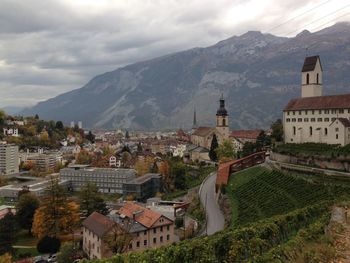 Town by mountain against cloudy sky