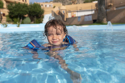 Toddler plays in the pool with children's floats. summer arrives in the northern hemisphere.