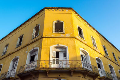 Low angle view of yellow abandoned building against clear sky