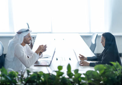 Side view of man using mobile phone while standing in office