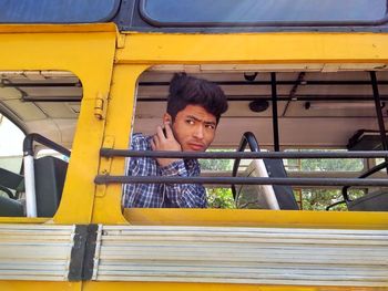 Man listening music while looking through bus window