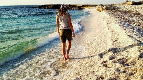 Full length rear view of woman walking at beach