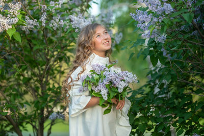 Happy girl standing by flowering plants