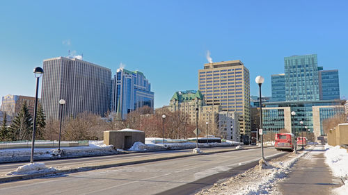City street by modern buildings against clear blue sky