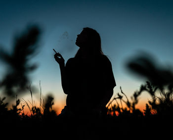 Silhouette man with woman standing against sky during sunset