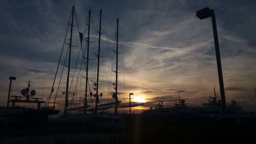 Silhouette ship moored at harbor against sky during sunset