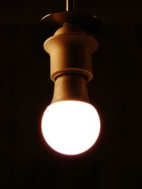 Low angle view of illuminated light bulb against black background