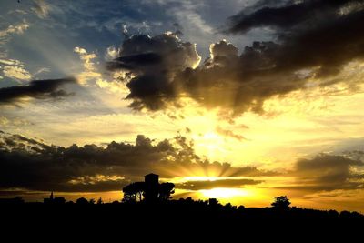 Silhouette people on field against sky during sunset