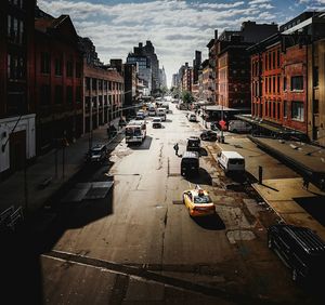 Cars on city street against sky