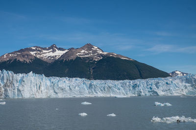 Scenic view of snow covered mountain by sea against sky