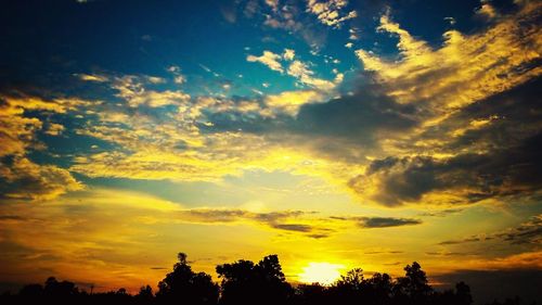 Silhouette of trees against cloudy sky