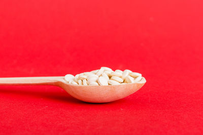 High angle view of pills in bowl on red background