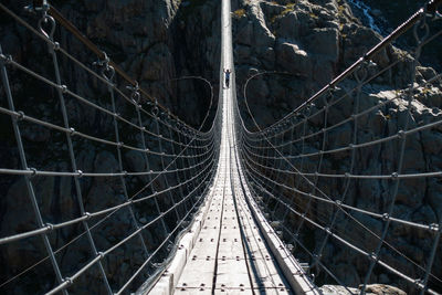 Mature man walking on footbridge over mountain