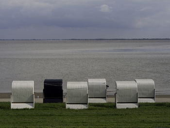 Hooded beach chairs on field against sky