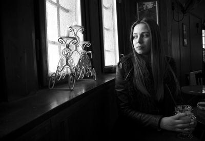 Portrait of young woman looking through window