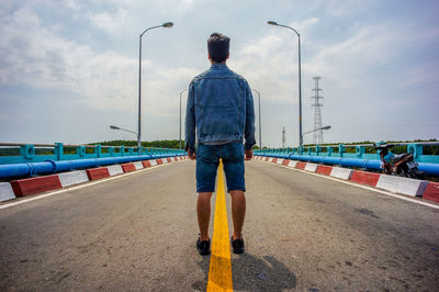 Rear view of man standing on road against sky