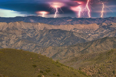 Firework display over mountains against sky