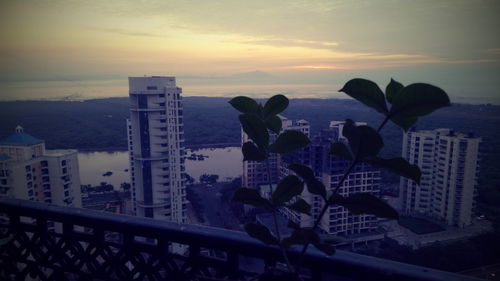 Cityscape by sea against sky during sunset