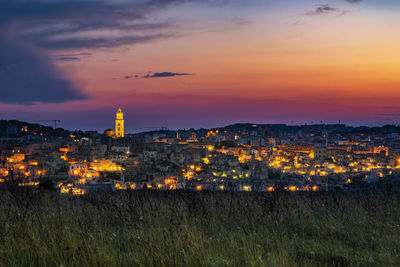 Illuminated buildings in city at sunset