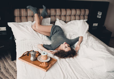 Young woman day dreaming while lying by food on bed