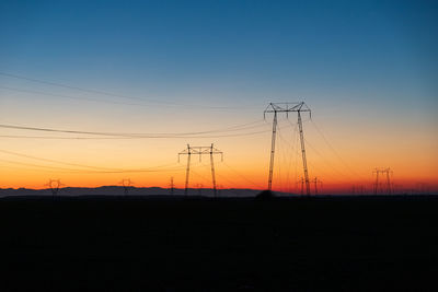 Silhouette electricity pylon against sky during sunset