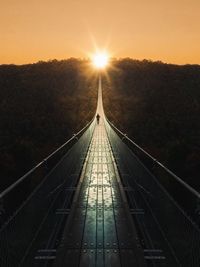 Footbridge against sky during sunset