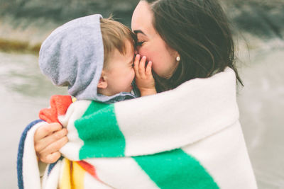 Side view of playful mother and son wrapped in blanket