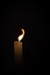 Close-up of lit candle against black background