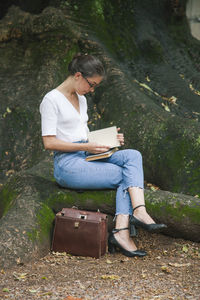 Full length of woman sitting on book