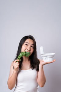 Portrait of young woman holding food against white background