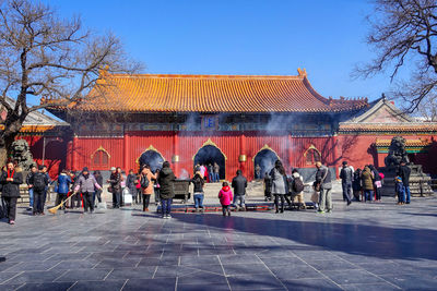 People in front of building against clear blue sky