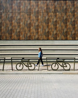 Side view of girl walking on footpath in city