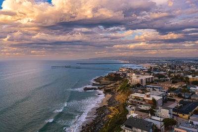 Aerial view of sea and buildings against sky during sunset