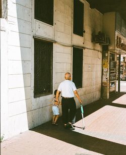 Rear view of people walking on sidewalk