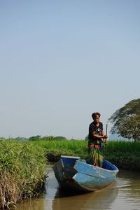 Man in boat on lake against clear sky